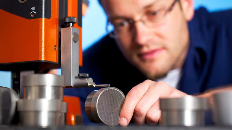 Engineer inspecting a metal sample during laboratory testing, illustrating practical engineering skills and hands-on technical training.