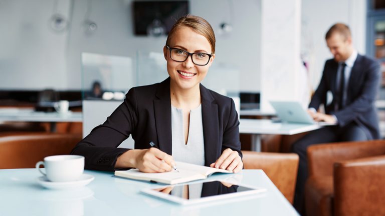 Businesswoman writing notes in a modern office, representing finance study and professional careers in Australia.