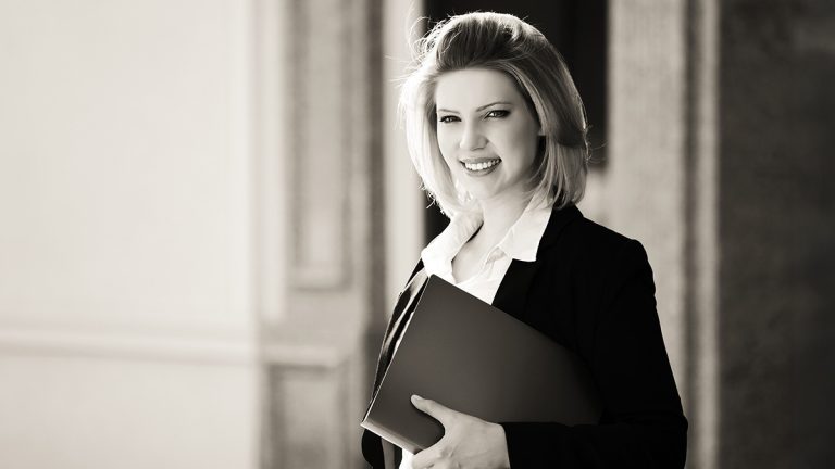 Smiling businesswoman holding a folder in a professional office setting.