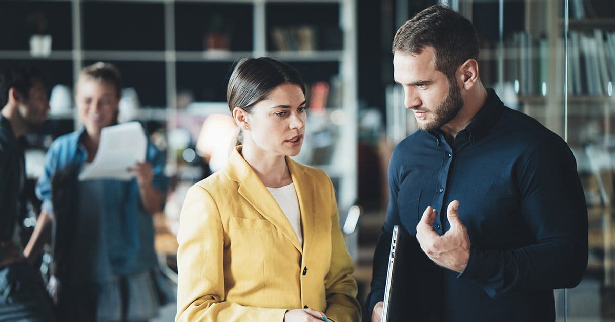 Two professionals in discussion while standing in office