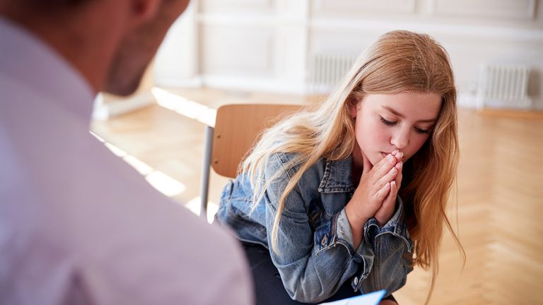 Teacher speaking with a distressed school student, illustrating educational wellbeing support and student emotional care.