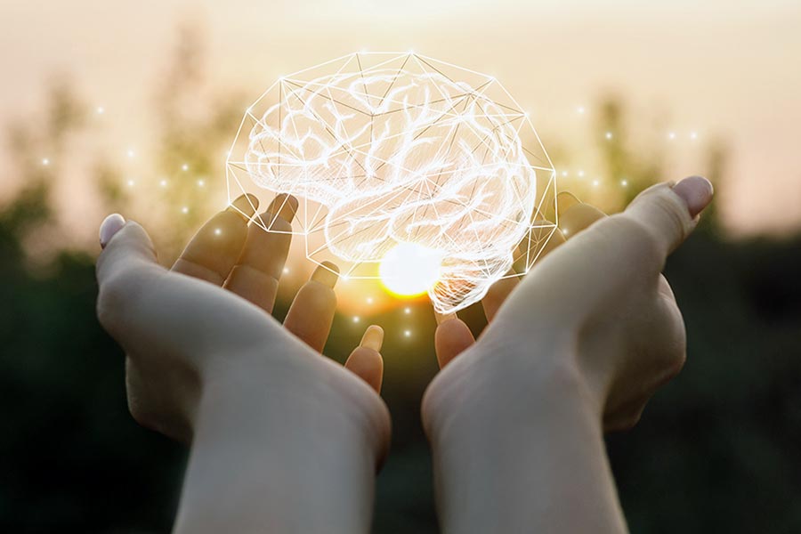 Sunlit graphic of human brain above outstretched hands