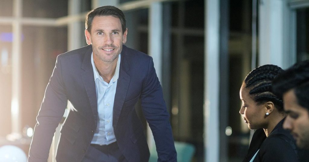 Professional man standing with hands on end of meeting table