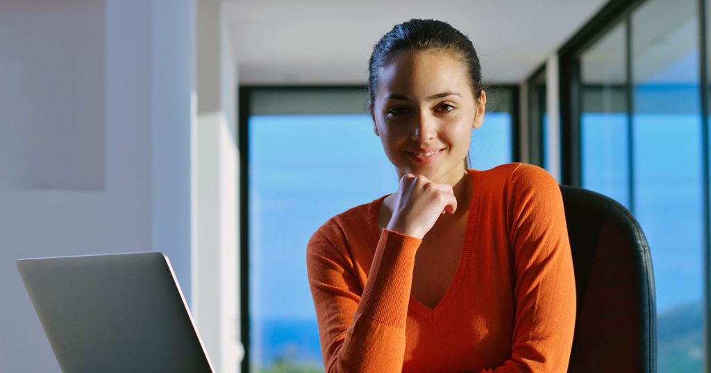 Young woman in confident pose in front of laptop