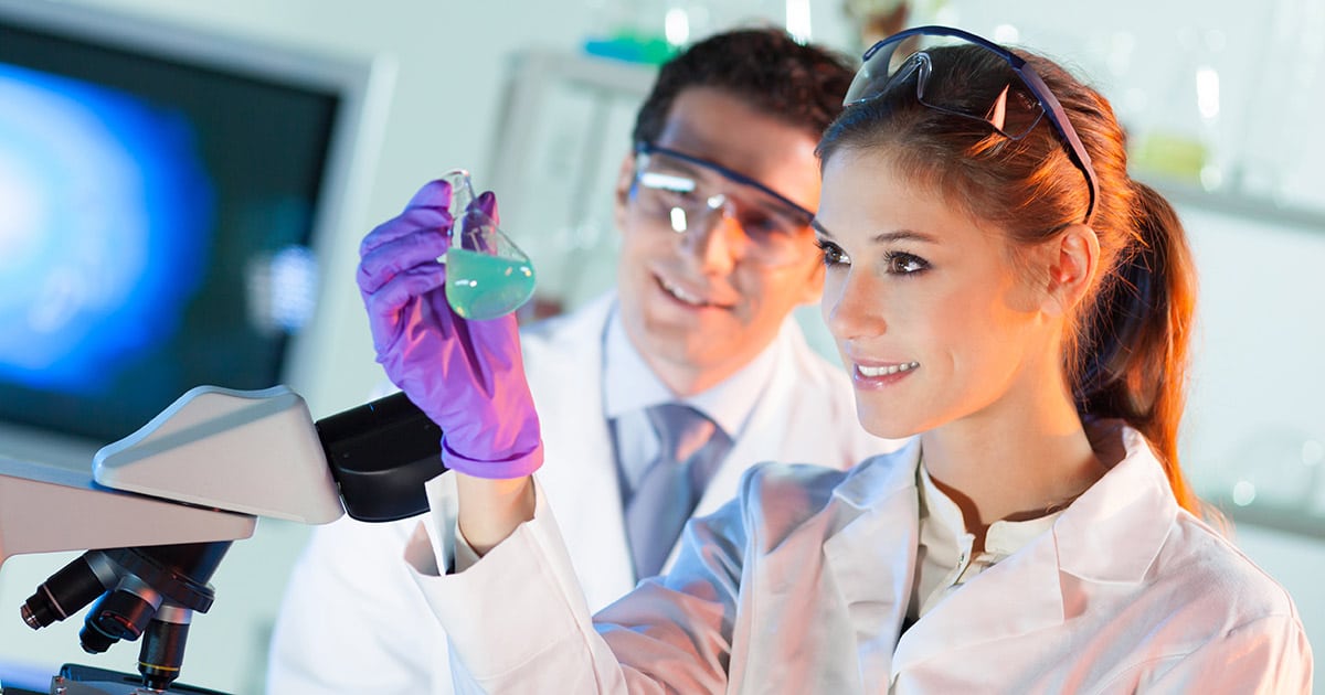 Scientists in a lab inspecting a substance contained in a glass flask