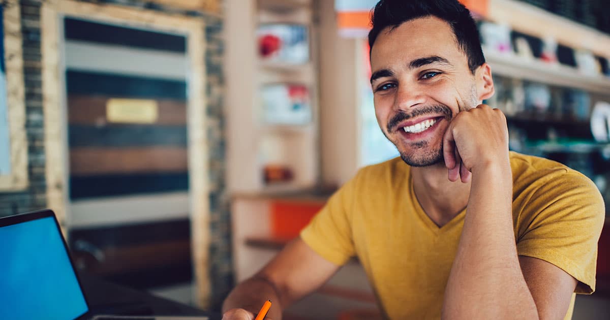 Man smiling while writing notes at desk