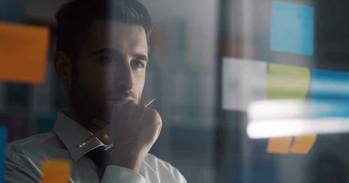 Business executive contemplating ideas on post-it notes