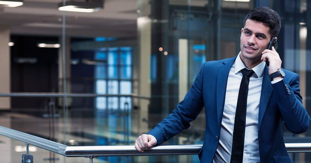 Businessman talking on phone while learning against a railing