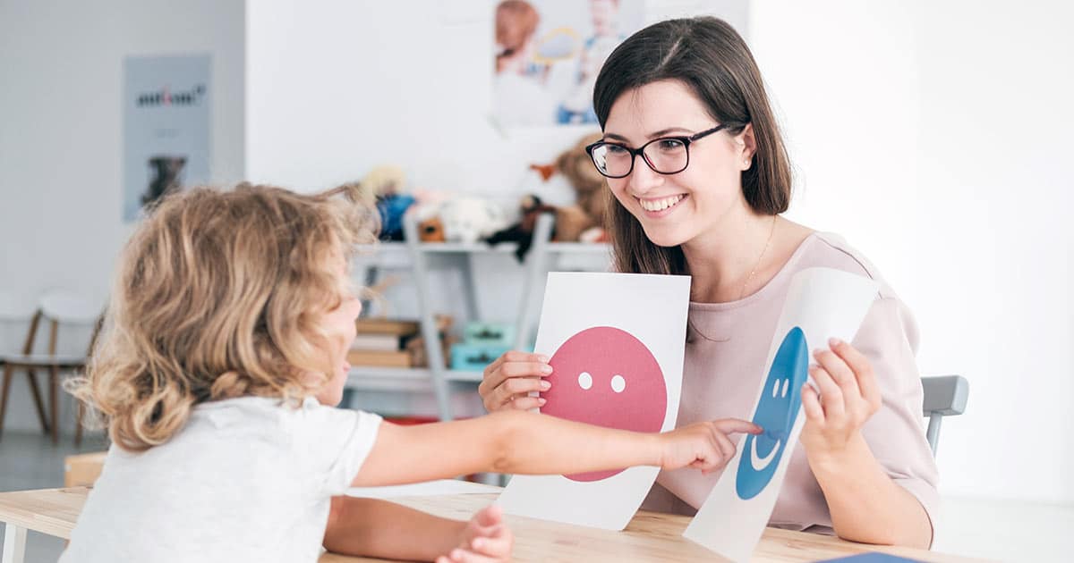 Child pointing to happy emoji with psychologist