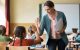Classroom teacher holding papers high fiving student