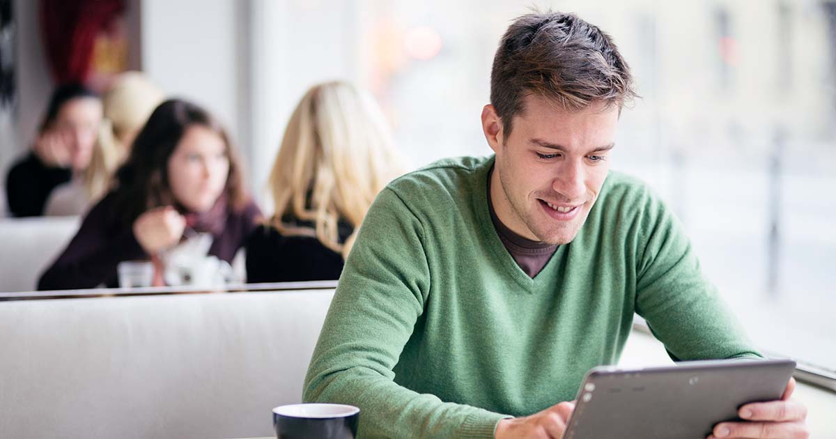 Young man using a computer device at a cafe