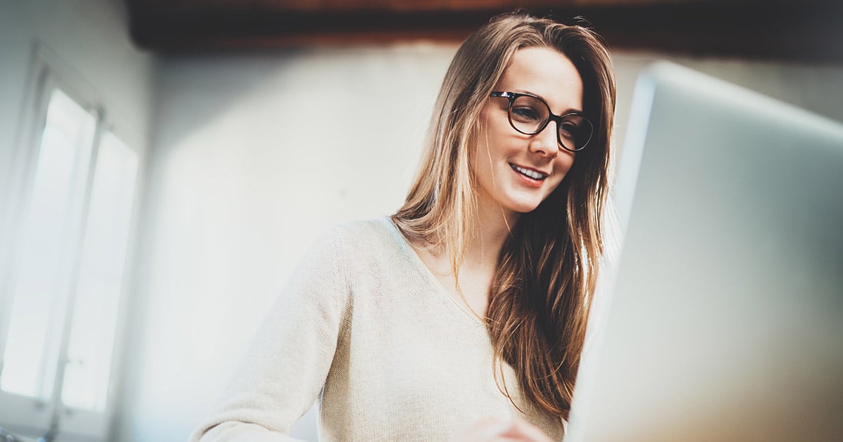 Woman smiling at she works at PC with large monitor