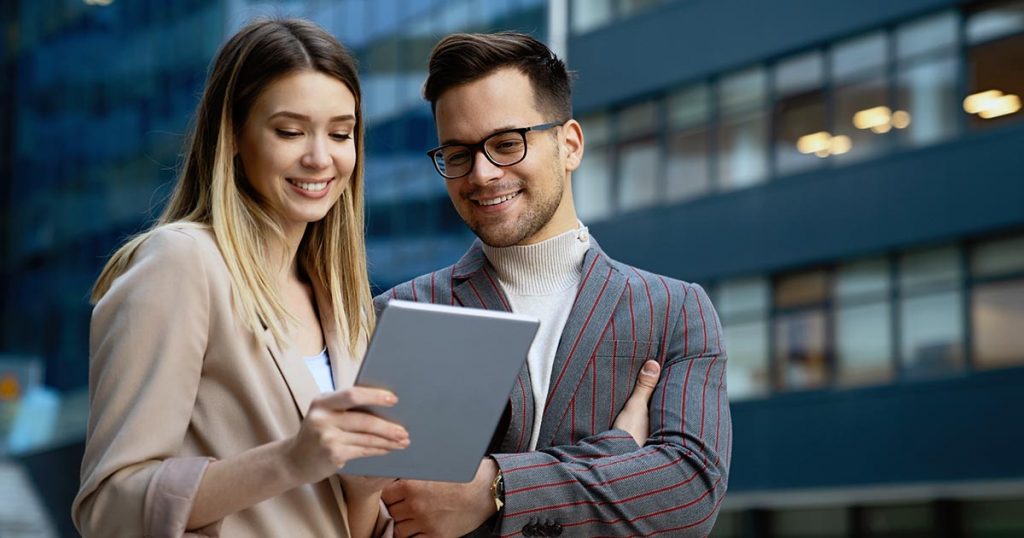 Male and female business professionals standing outside looking at computer tablet