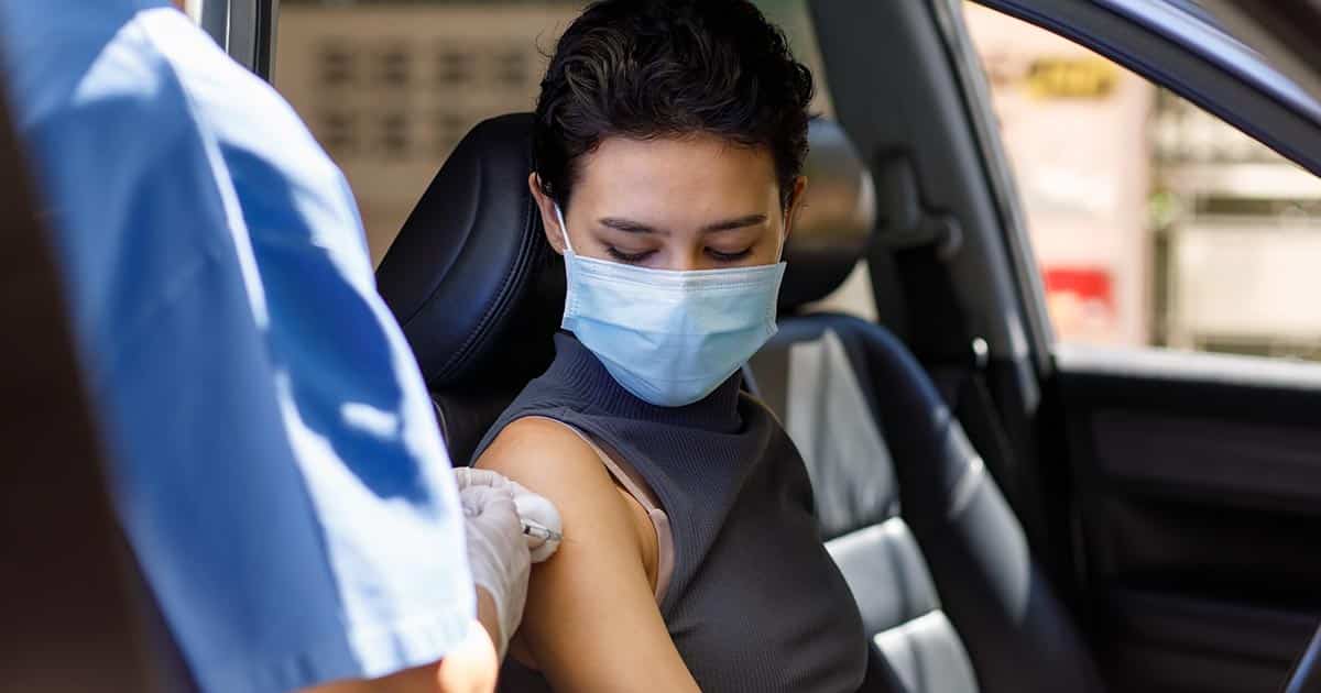 Woman receiving drive-through car vaccination