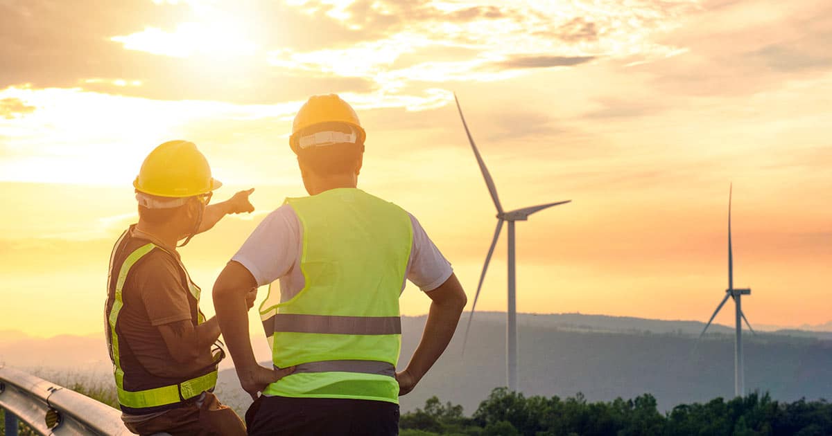 Engineers overlooking wind turbines at sunset