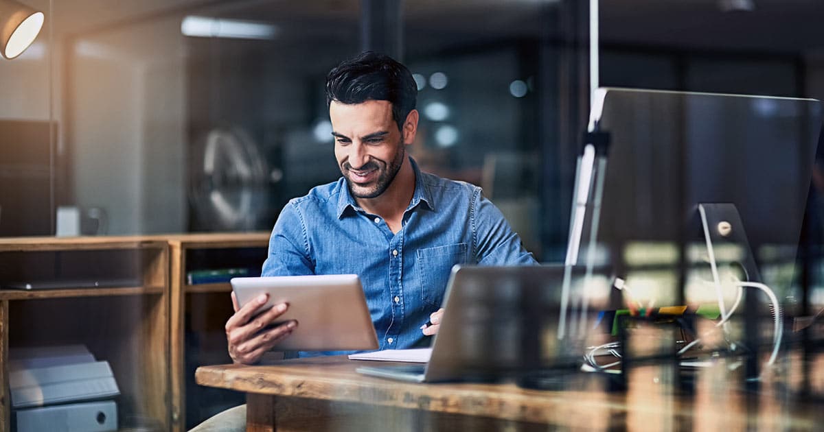 Male entrepreneur or postgraduate student at desk looking at computer tablet