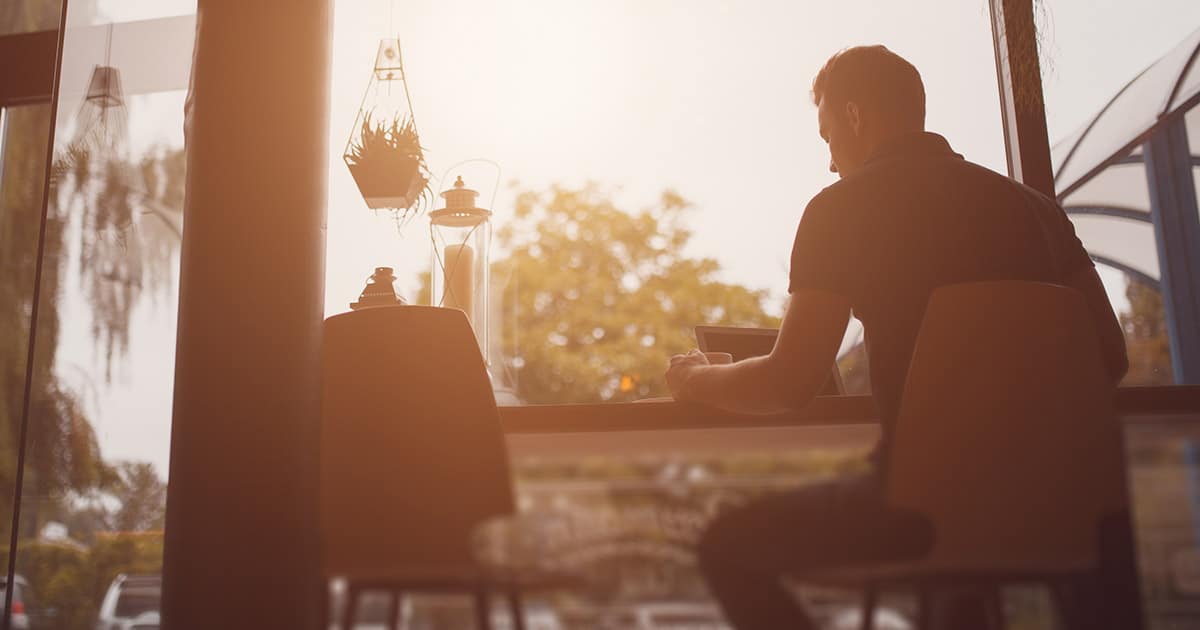 Man at sunlit desk working on laptop