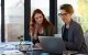 Female professionals consulting over laptop in large office suite