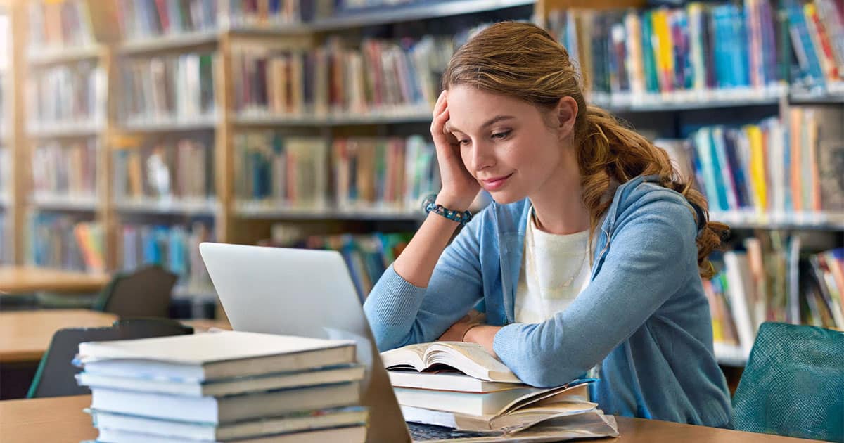 Female university student studying hard in library