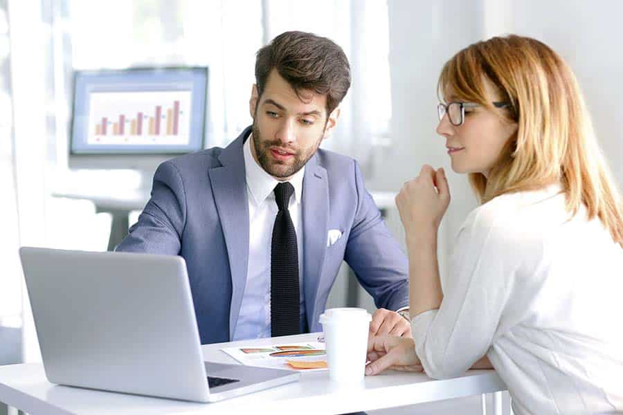 Professional man advising female client with reference to computer screen