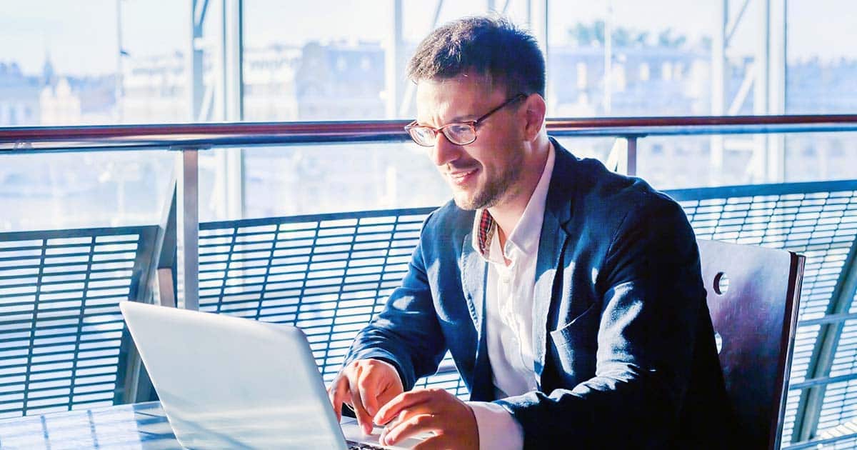 Professional man working at laptop near window