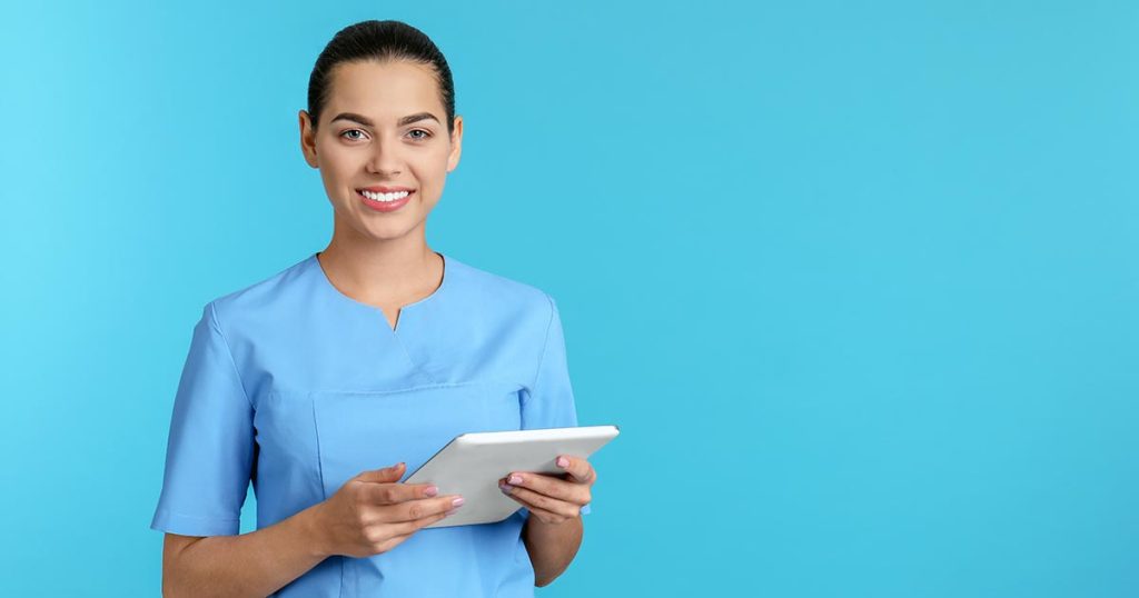 Woman in scrubs holding computer tablet