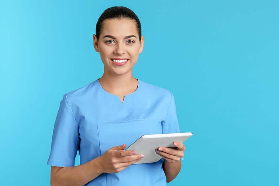Female health professional in scrubs with computer tablet