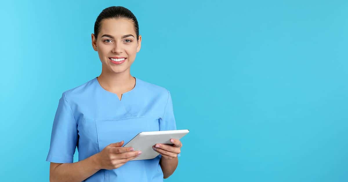 Woman in scrubs holding computer tablet