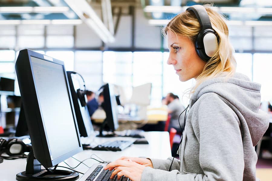 Woman at computer in office with headphones