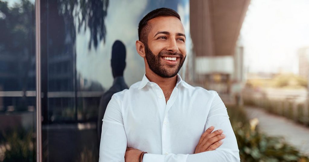 Man in white shirt smiling outside commercial building