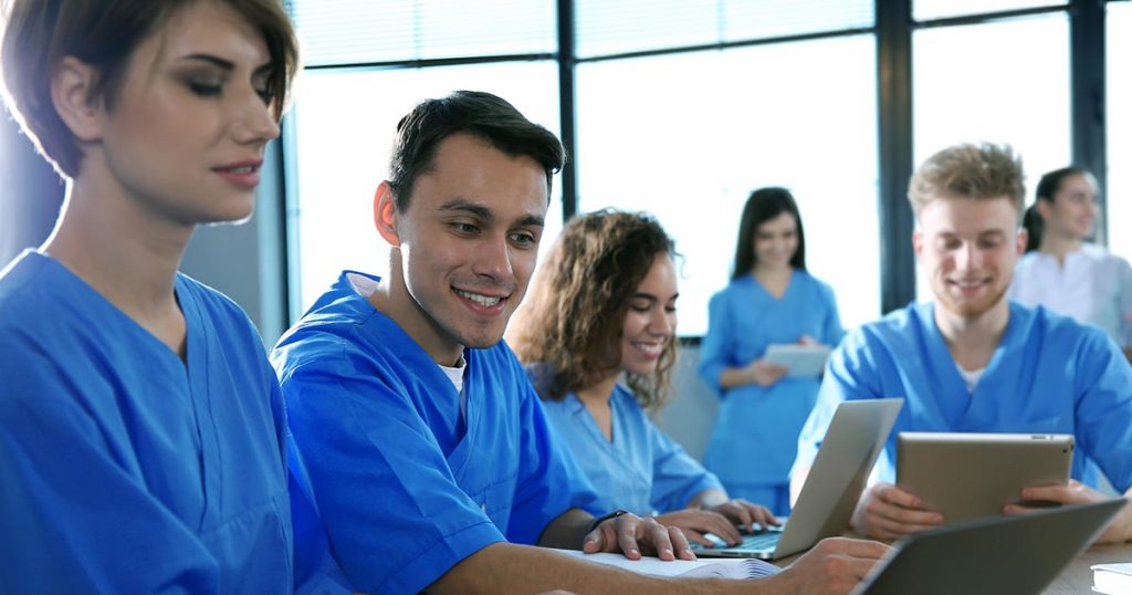 Health professionals in blue scrubs in a large meeting