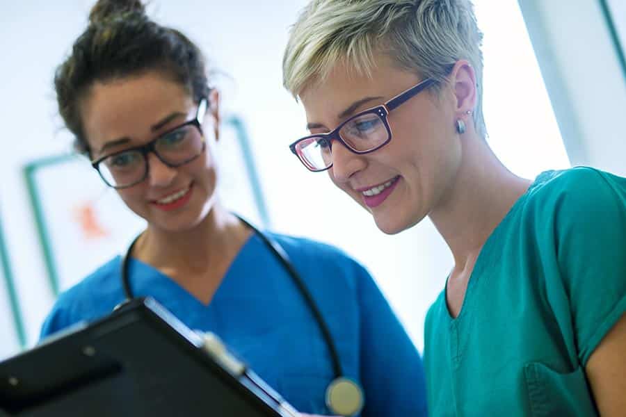 Two female medical professionals looking at clipboard