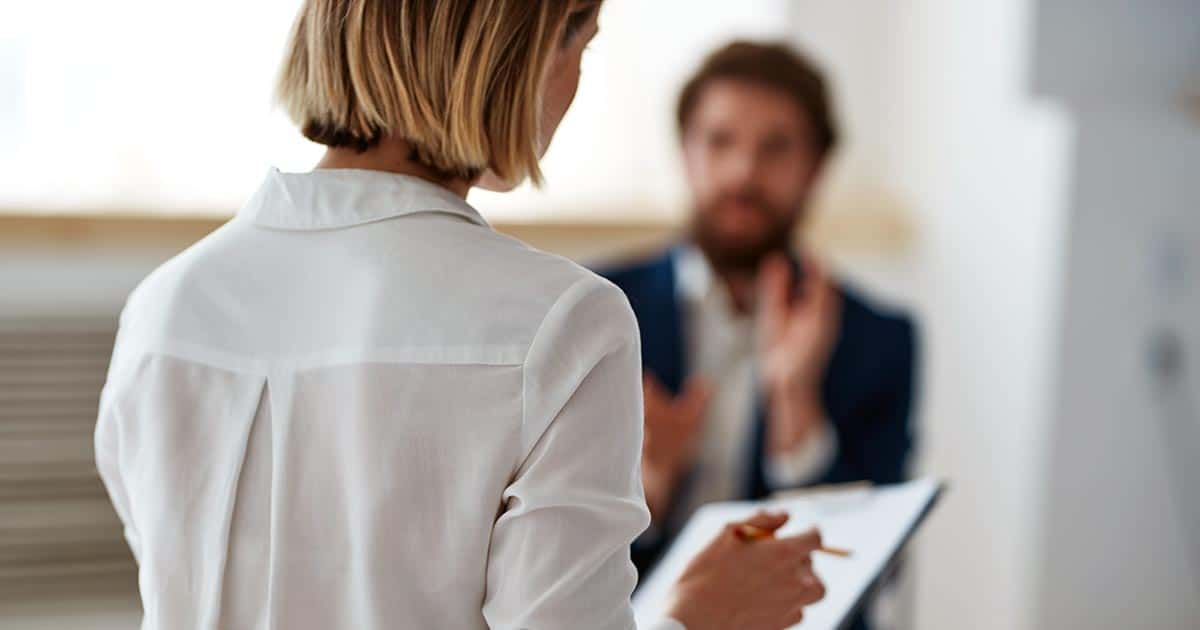 Woman take notes during a discussion with a man