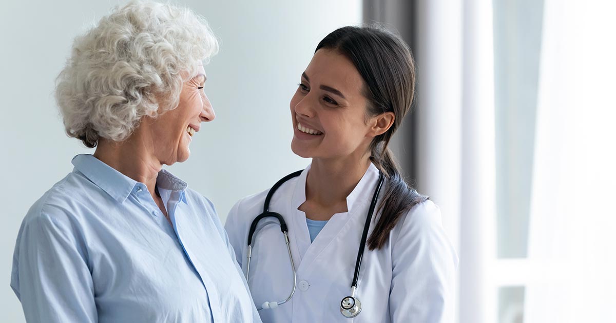 Happy helpful nurse or doctor smiling at woman