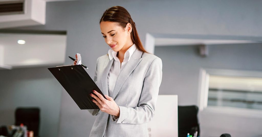 Professional woman dressed in light colours using clipboard