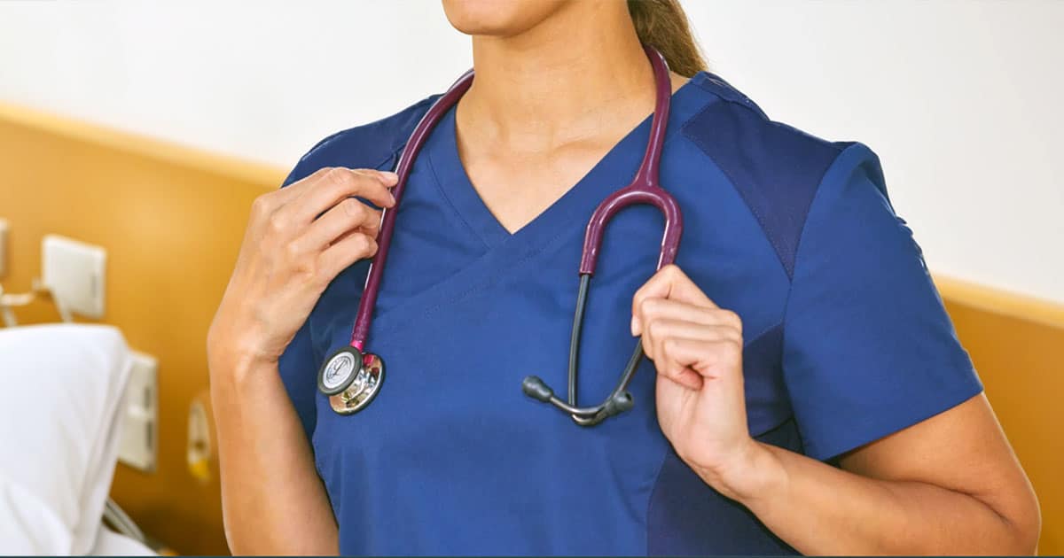 Healthcare professional in dark blue scrubs holding stethoscope