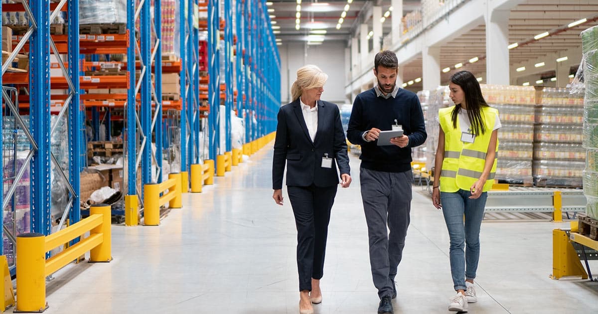 Work colleagues look at clipboard while walking through a warehouse or product distribution centre