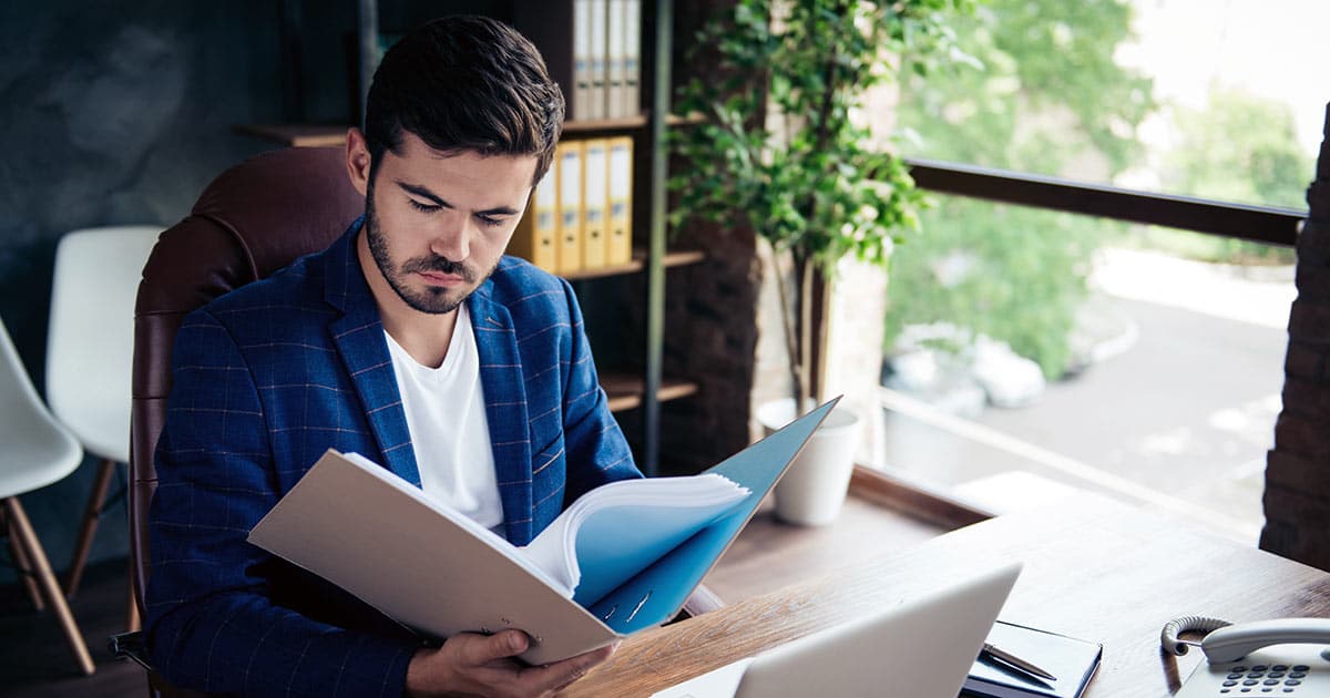 Male executive at desk looking through folder