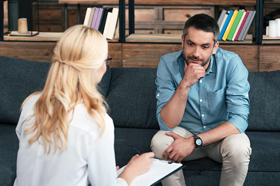 Man reflecting while female professional takes notes