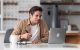 Man taking notes using laptop on kitchen table