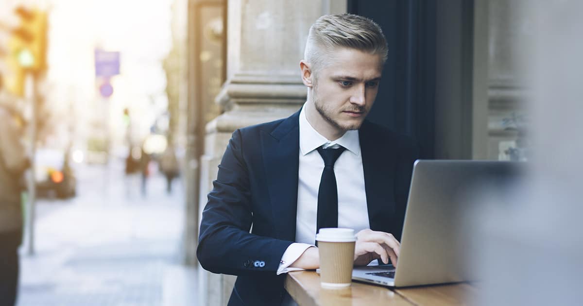 Professional man working on laptop at outdoor café on city street