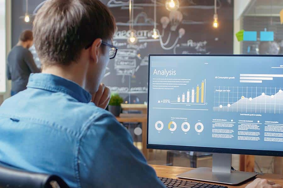 Man in office looking at computer screen showing charts and analysis