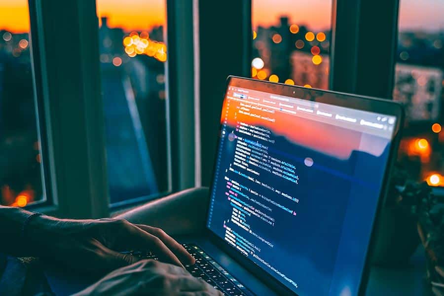 Man coding on laptop in corner office