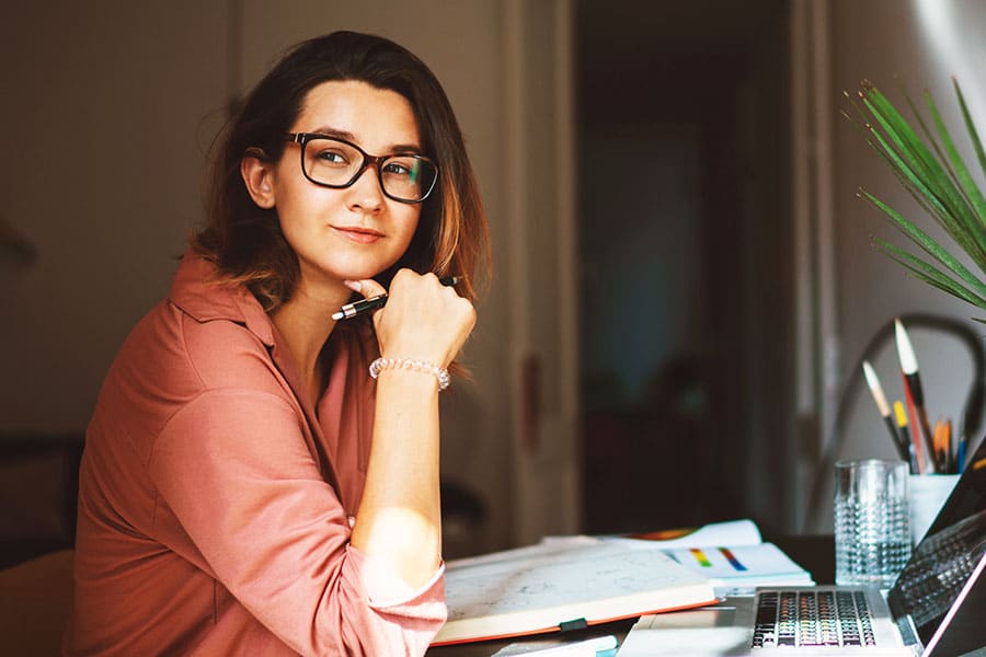 Woman wearing glasses looking up from computer