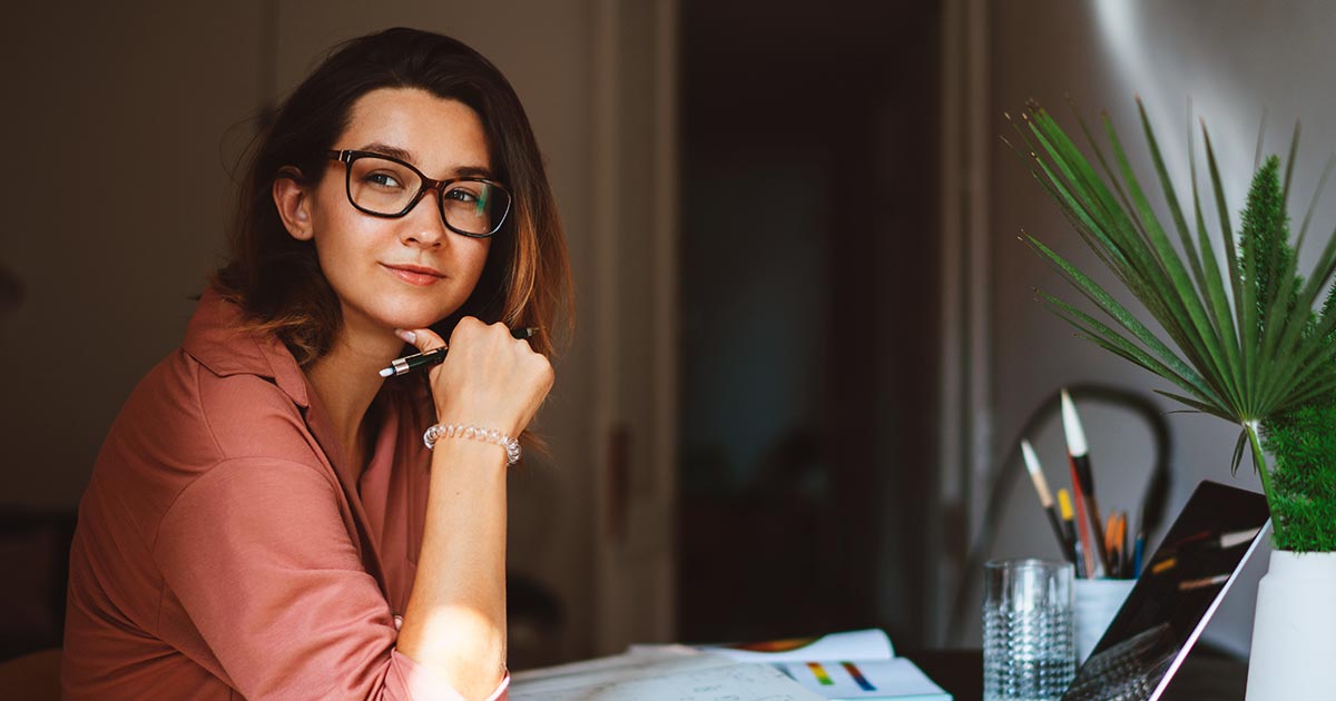 Woman with glasses smiling at desk