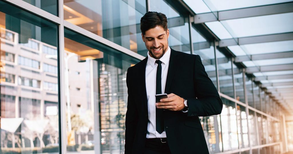 Business smiling while walking and looking at phone