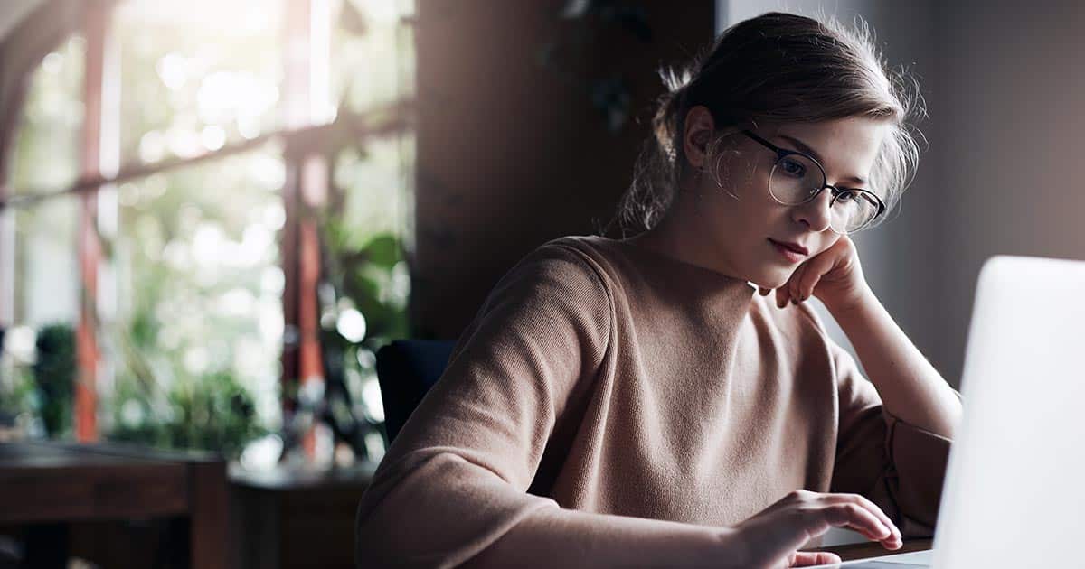 Woman wearing glasses using laptop at home