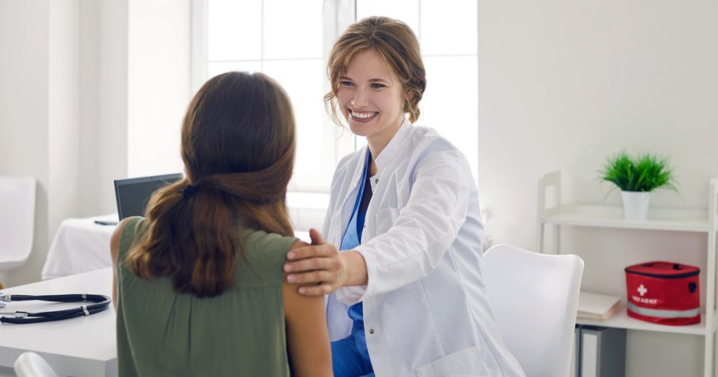 Female healthcare professional with hand on shoulder of client