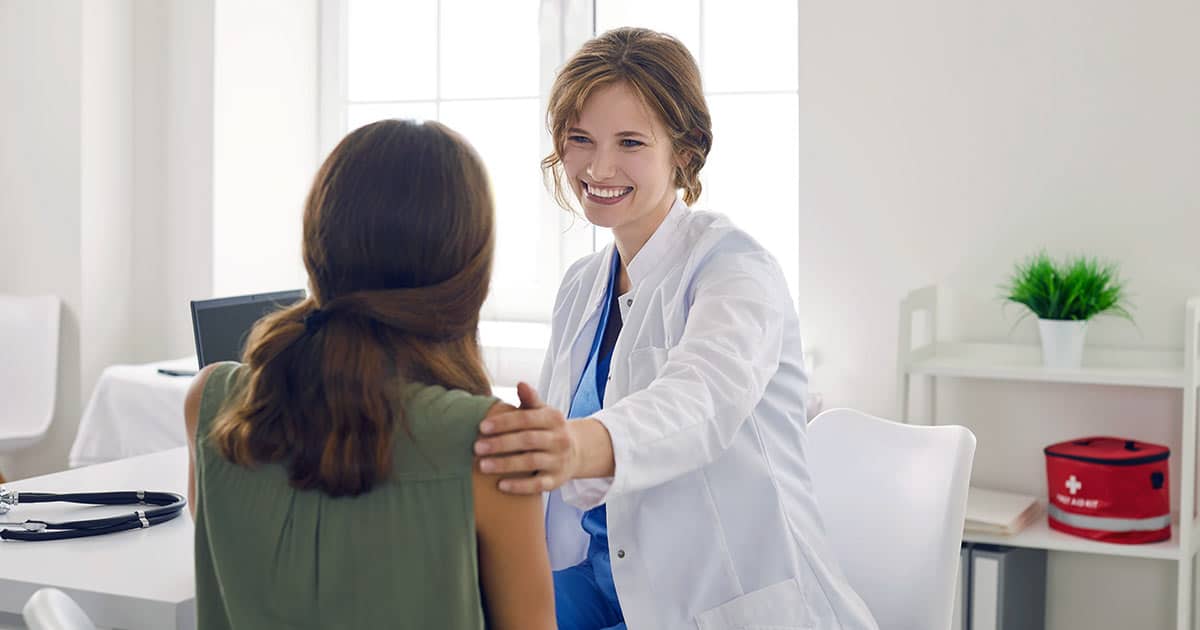 Female healthcare professional with hand on shoulder of client
