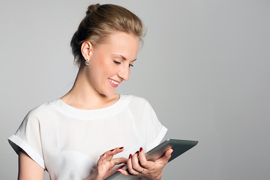 Woman smiling as she uses computer tablet